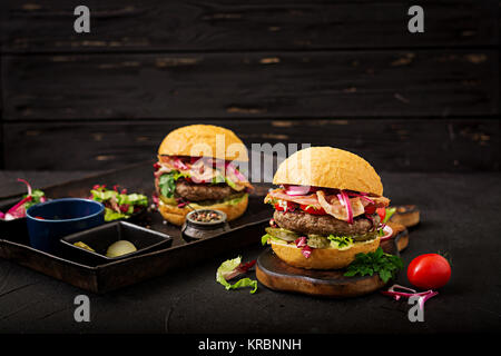 Grande panino - hamburger burger con carne di manzo, pomodoro, cetriolo sottaceto e pancetta fritta Foto Stock