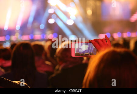 Ragazzina prende una foto con lo smartphone durante il concerto dal vivo Foto Stock