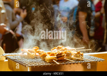 Capesante di mare e uova ​​urchin spillone grill con fumo, giapponese street food al mercato del pesce, Giappone. messa a fuoco selettiva. vintage foto e film di stile Foto Stock