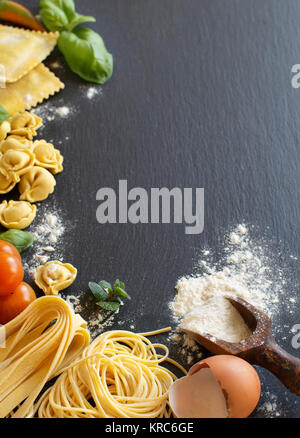 La pasta fresca e gli ingredienti su un bordo scuro Foto Stock