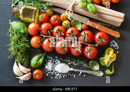 La cucina italiana ingridients : pomodori ciliegia, erbe aromatiche, pasta e olio di oliva Foto Stock