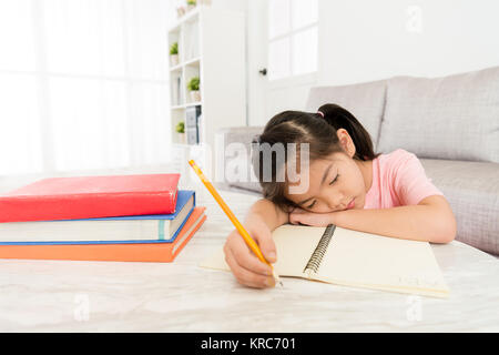 Piuttosto giovane ragazza di capretto studente appoggiata sul soggiorno escursioni a dormire quando ella lo studio studio inglese textbook sensazione di stanchezza. Foto Stock