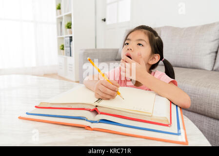 Carino ragazza giovane studente iscritto a scuola compiti a casa stanco assonnato e sbadigliamento desidera riposare. Foto Stock