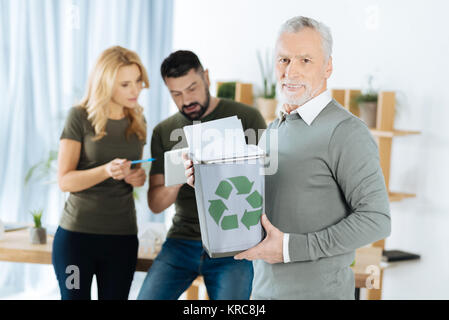 Smart man tenendo un bin con carta riciclata in esso Foto Stock