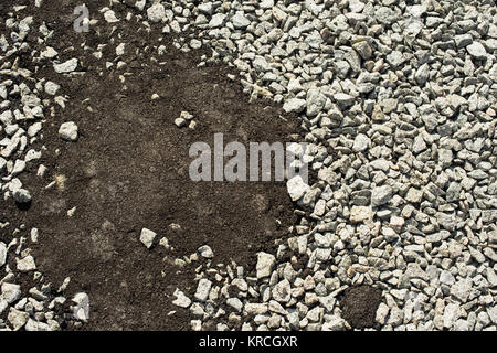 Pietre frantumate parzialmente coperto con nuovo asfalto calcestruzzo Foto Stock