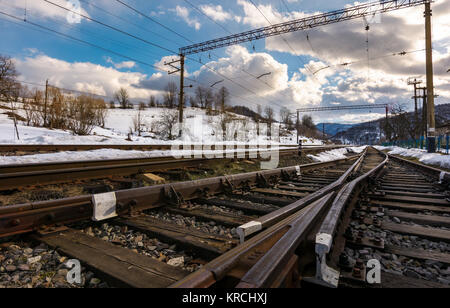 Vecchia ferrovia in montagna in inverno in un giorno nuvoloso. sfondo di trasporto Foto Stock