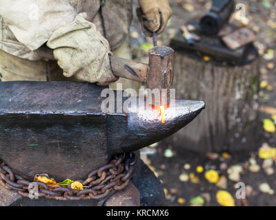 Elaborazione di fabbro red hot tondino di ferro sull'incudine Foto Stock