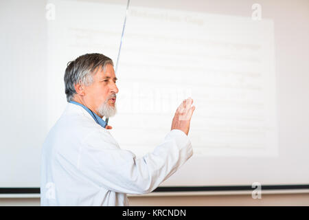 Senior professore di chimica dando una lezione nella parte anteriore dell'aula piena di studenti (SHALLOW DOF dai toni di colore immagine) Foto Stock
