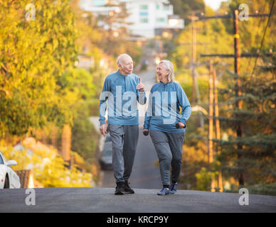 Coppia senior a piedi lungo la strada sulla collina Foto Stock