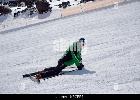 Sorridente sciatore disteso con gli sci sulla pista da sci Foto Stock