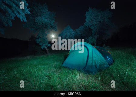 Tenebrologo con tenda da campeggio e la luna sul cielo nero Foto Stock