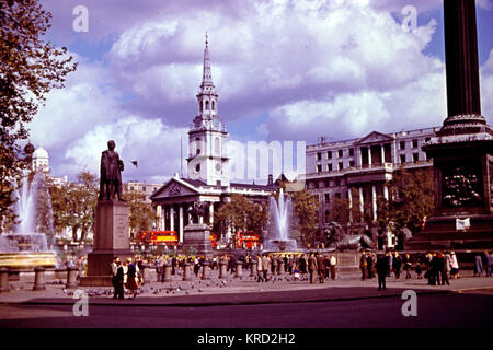 Una scena diurna a Trafalgar Square, Londra, con due fontane in azione, persone e piccioni, e la chiesa di St Martin in the Fields sullo sfondo. Foto Stock