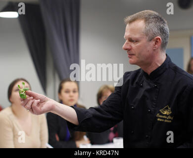 La Bielorussia Minsk, Marzo 21, 2017. Lezione aperta sulla cucina cucina francese. Il cuoco mantiene i verdi in mano.Lo chef prepara. Lo Chef guarda al cibo Foto Stock