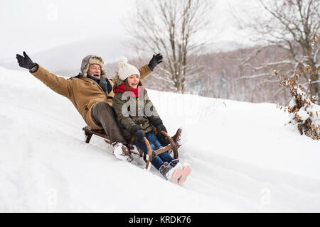 Il nonno e la bambina lo slittino su un giorno d'inverno. Foto Stock