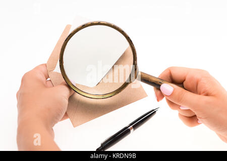 Le mani femminili con busta con lente di ingrandimento su sfondo bianco Foto Stock