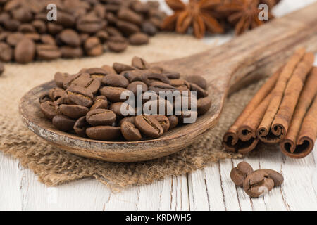 I chicchi di caffè in un cucchiaio di legno sul vecchio tavolo in legno. Foto Stock