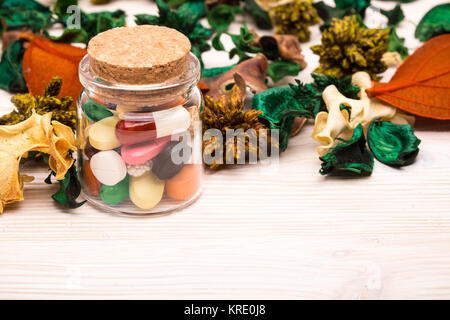 Varie pillole e capsule con verde e foglie di colore arancione Foto Stock