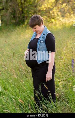 Foto di maternità di una giovane donna con capelli corti pixie tagliato nel suo terzo trimestre con il bambino. Foto Stock