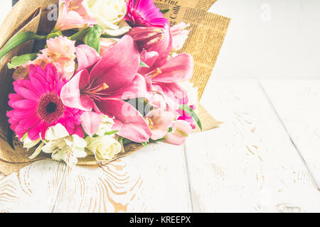 Un mazzo di fiori da un giglio, gerbera, rose bianche e alstroemeria su un bianco tavolo di legno. Una vacanza, un regalo Foto Stock