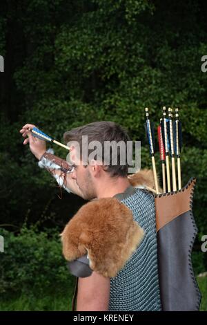 giovane arciere medievale con catena raggiunge per freccia, con arco in mano nella natura Foto Stock