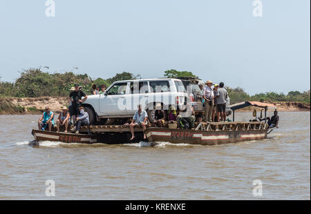 I suv e i passeggeri a bordo di una barca di traghetto sul Fiume Mania. Madagascar, Africa. Foto Stock