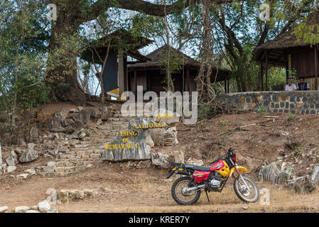 Un rosso moto parcheggiata di fronte dei Tsingy de Bemaraha Parco Nazionale di ingresso. Madagascar, Africa. Foto Stock