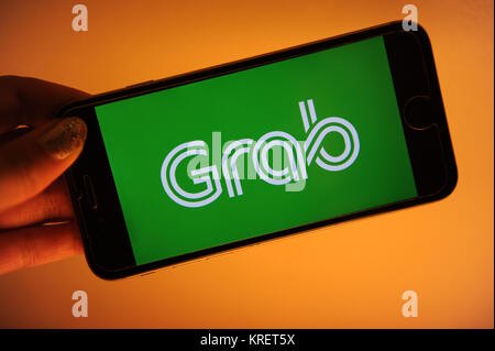 Grab, il viaggio salutando il logo della società su un telefono Foto Stock