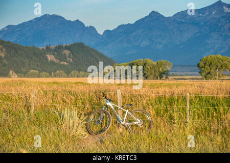 Bike poggia contro il recinto con Teton Mountain Range salendo in background, Grand Tetons National Park, Teton County, Wyoming Foto Stock