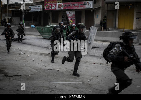 Ramallah, West Bank. Xx Dec, 2017. Esercito Israeliano soldati corrono verso i dimostranti palestinesi dueing scontri a seguito di proteste contro il presidente statunitense Donald Trump per la decisione di riconoscere Gerusalemme come capitale di Israele, nel villaggio di Qalandiya, vicino a Ramallah in Cisgiordania, 20 dicembre 2017. Credito: Ilia Yefimovich/dpa/Alamy Live News Foto Stock