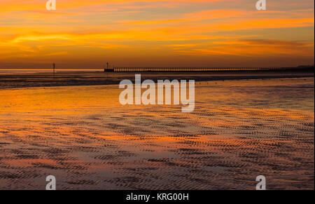 Red Sky dopo il tramonto su una spiaggia a bassa marea in inverno, nel West Sussex, in Inghilterra, Regno Unito. Foto Stock