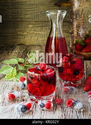 Estate berry lemonade con frutti di bosco surgelati e una brocca su un di legno tavolo rustico, il fuoco selettivo Foto Stock