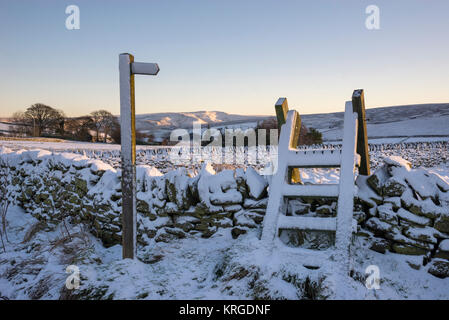 Sentiero segno e stile in legno su un nevoso inverno mattina vicino a Rowarth nel Derbyshire, Inghilterra. Foto Stock