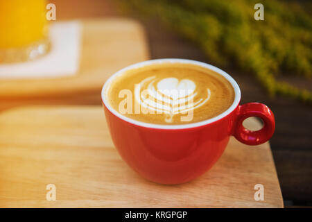 Red tazza di caffè in un giorno di estate con fiori in background Foto Stock