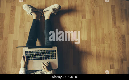 Il lavoro di relax a casa: concetto con una ragazza seduta sul pavimento con laptopand altri strumenti Foto Stock