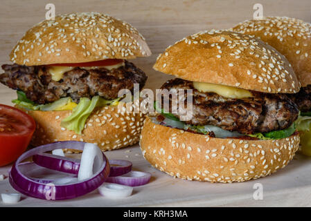 Tre hamburger freschi poggiare sul bordo. Foto Stock