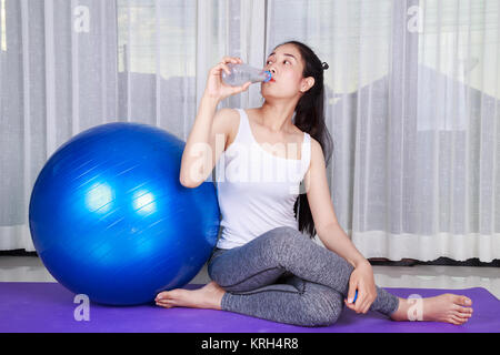 Sport donna acqua potabile dopo esercizio con palla fitness Foto Stock