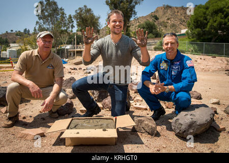 Attore Matt Damon, che stelle come astronauta della NASA Mark Watney nel film "Il marziano", sorride dopo aver compiuto il suo canto di stampe in cemento presso il Jet Propulsion Laboratory (JPL) Mars cantiere, mentre Mars Science Progetto Lab Manager Jim Erickson, sinistro e l'astronauta della NASA Drew Feustel a guardare, Martedì, Agosto 18, 2015, presso il JPL di Pasadena, in California. Mentre a JPL Damon incontrare con gli scienziati della NASA e tecnici che hanno servito come consulenti tecnici sulla pellicola. Il film ritrae una visione realistica del clima e la topografia di Marte, sulla base dei dati della NASA, e alcune delle sfide che la NASA volti come ci prepariamo Foto Stock