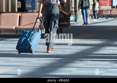 Tbilisi, Georgia, 11-07-2017: un uomo con una valigia blu su ruote in aeroporto area di attesa a bordo del piano. Foto Stock