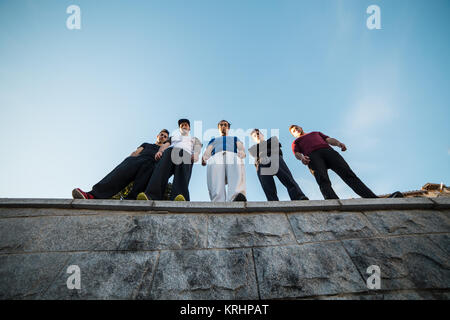 Dal al di sotto del gruppo di professionisti di parkour in piedi e in posa sulla parete. Foto Stock