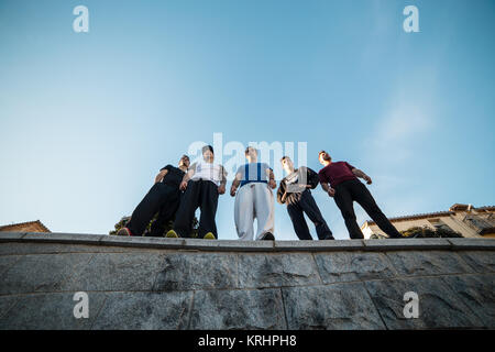 Dal al di sotto del gruppo di professionisti di parkour in piedi e in posa sulla parete. Foto Stock