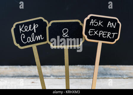 Mantenere la calma e a chiedere un esperto messaggio scritto con un gessetto su mini etichette di Blackboard Foto Stock