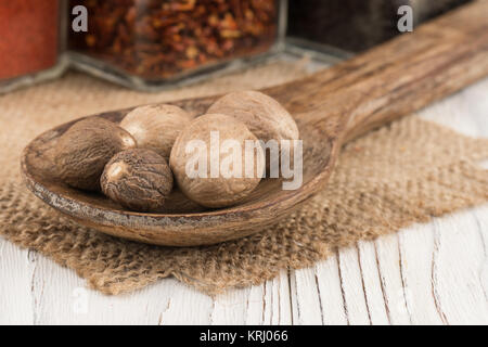 Noce moscata in un cucchiaio di legno sul vecchio tavolo in legno. Foto Stock