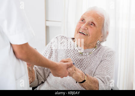 Paziente Senior tenendo le mani del medico donna Foto Stock