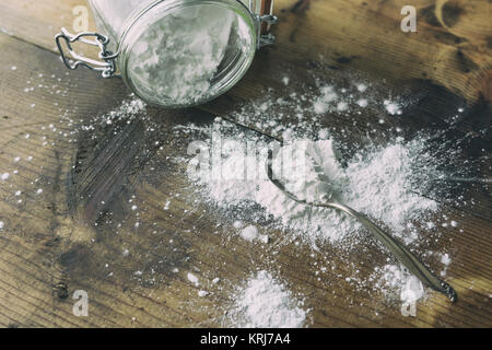 Arrow-polvere versato su un vecchio tavolo di legno. Mostrato con antichi cucchiaio d'argento e vaso di grandi dimensioni. Foto Stock