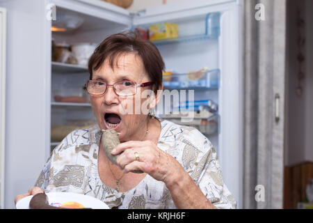 Donna senior di mangiare carne di maiale salsiccia di fegato Foto Stock