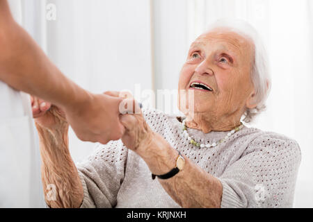 Paziente Senior tenendo le mani del medico donna Foto Stock