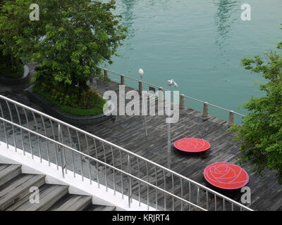 Due sedie rosse sul ponte di legno dal fiume Foto Stock