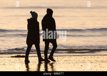 Silhouette di un paio di fare una passeggiata in riva al mare nella luce della sera. Foto Stock