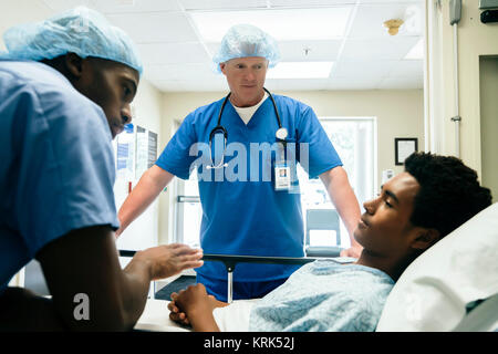 Gli infermieri parlando con il ragazzo nel letto di ospedale Foto Stock