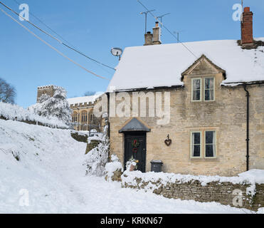 Chedworth village cottage e chiesa nel dicembre neve. Chedworth, Cotswolds, Gloucestershire, Inghilterra Foto Stock